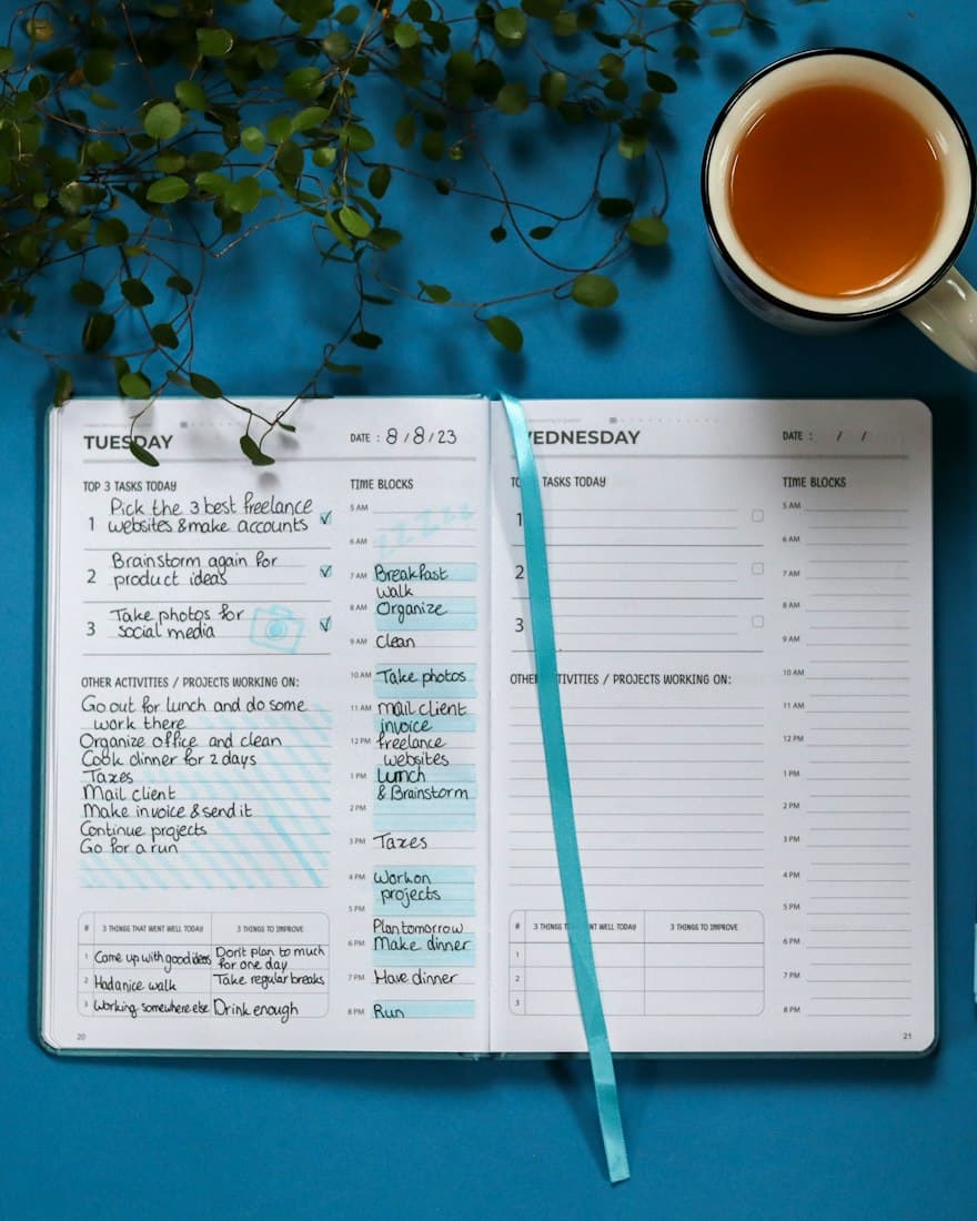 An open planner with a handwritten task list next to a cup of tea