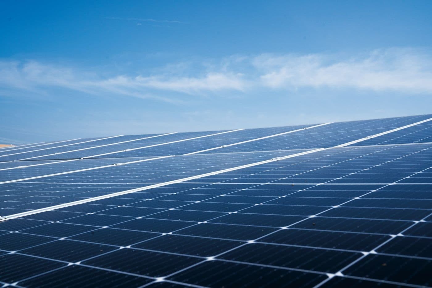 Rows of blue solar panels on a roof under a clear sky