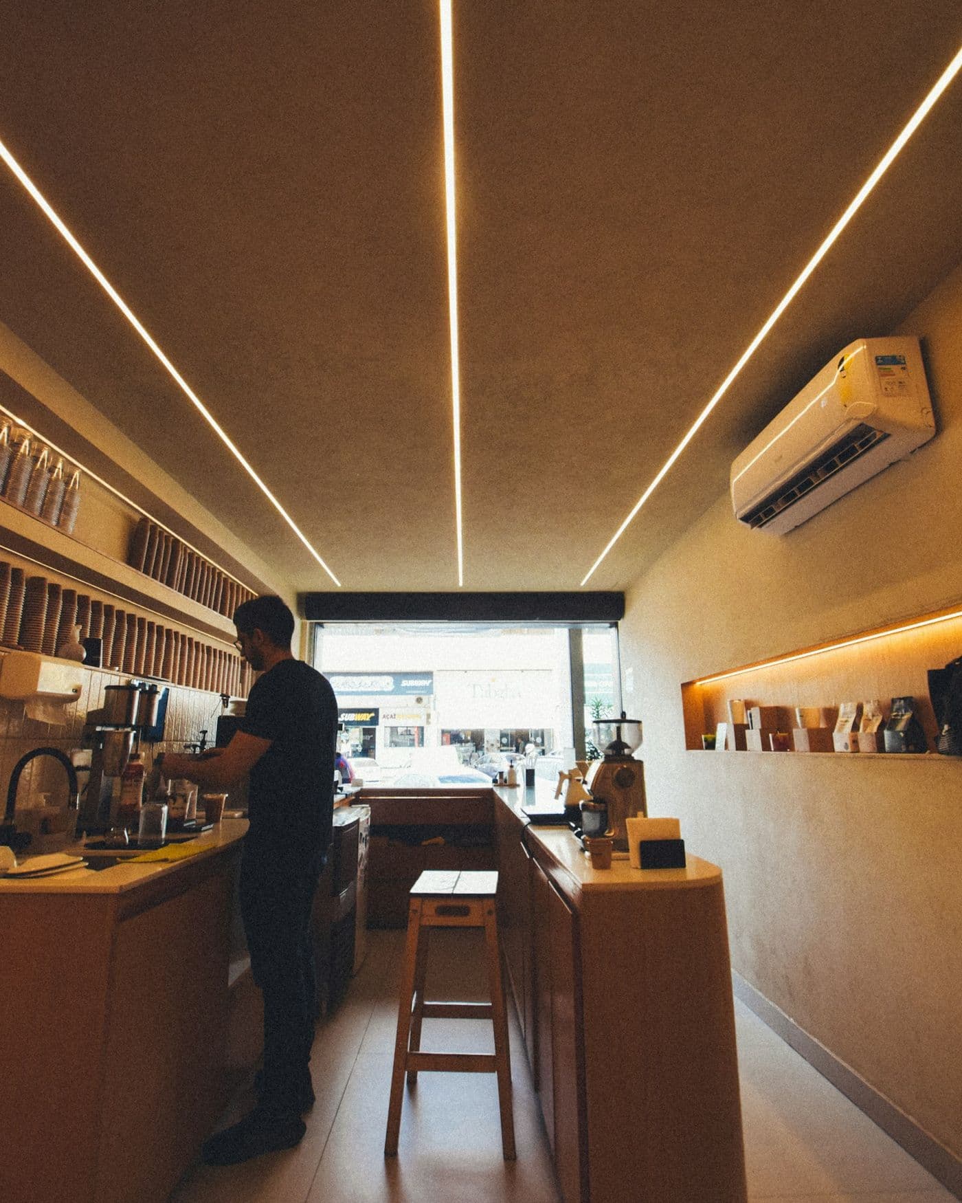 A barista preparing coffee behind a wooden counter in a minimalist café